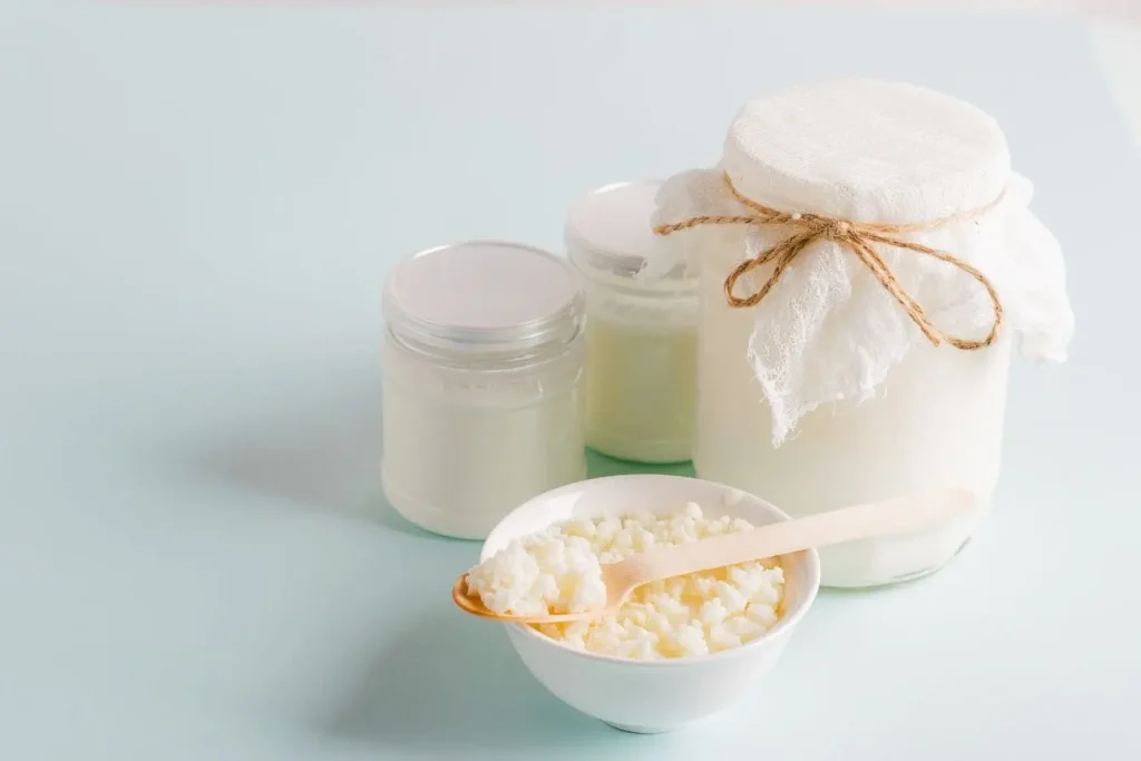 Laits fermentés en bocaux et grains de kéfir dans un bol, image liée aux bienfaits digestifs et immunitaires