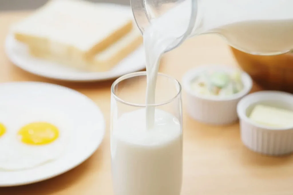 Lait versé dans un verre entouré d’aliments du matin, image liée à une dégustation de lait de brebis