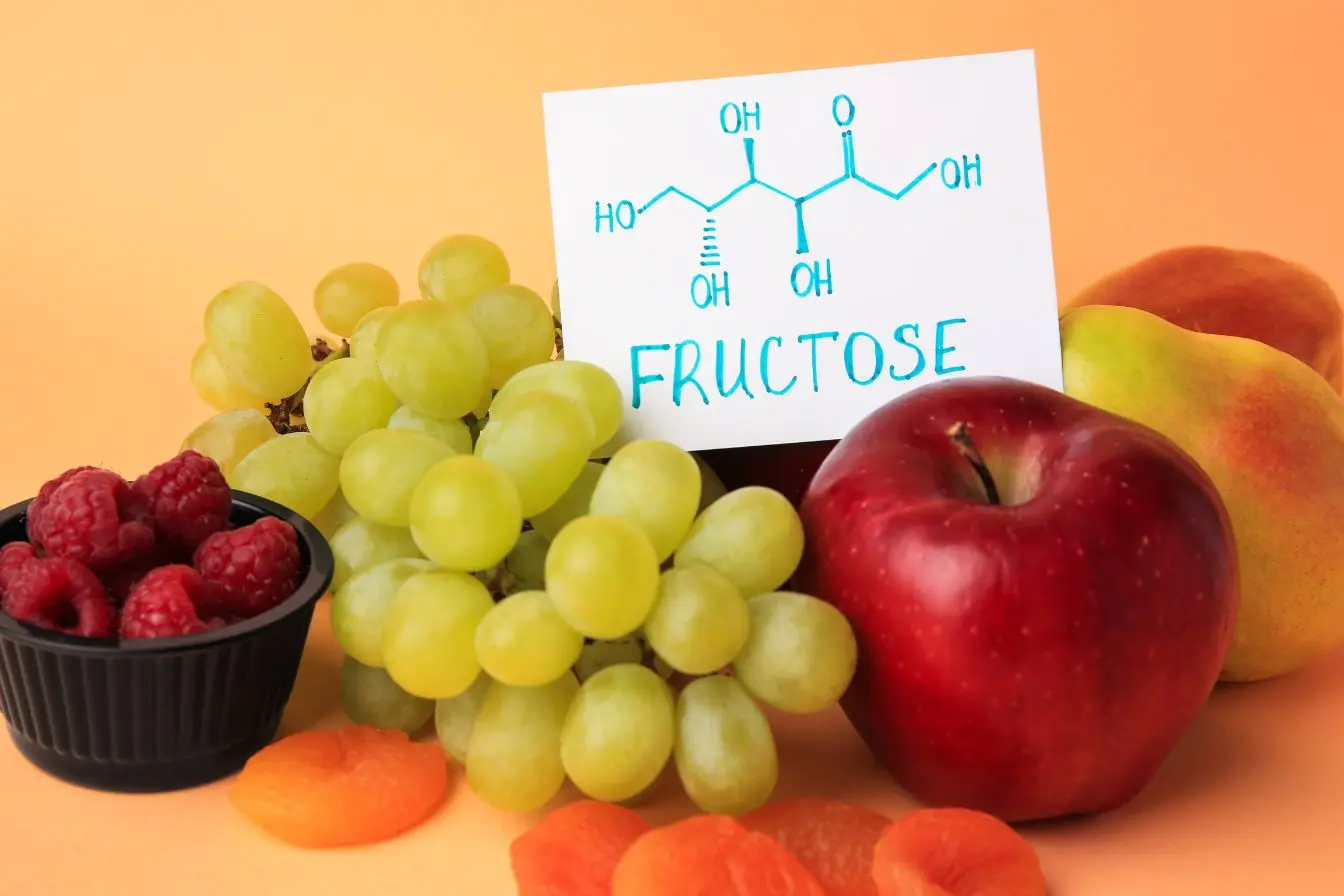 Fruits variés posés autour d’une carte chimique du fructose, image illustrant la présence naturelle du sucre