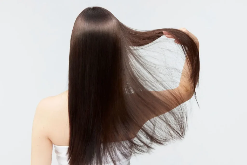 Chevelure longue et brillante tenue sur le côté illustrant les effets visibles du traitement Cystine B6 Bailleul