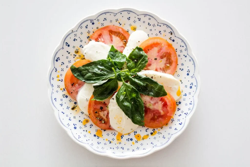 Assiette de tomates et mozzarella avec basilic illustrant une recette emblématique du régime méditerranéen