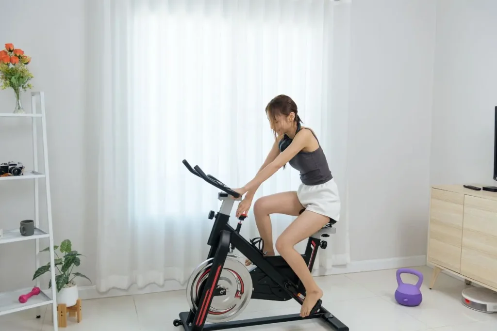 Séance de cardio à la maison sur vélo stationnaire illustrant une activité physique pour limiter la douleur intercostale liée au stress
