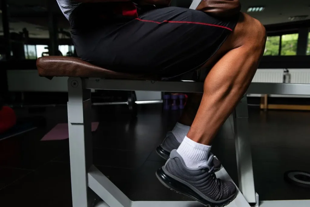 Personne assise sur banc de musculation, jambes visibles et définies, image illustrant un entraînement ciblé pour maigrir des mollets