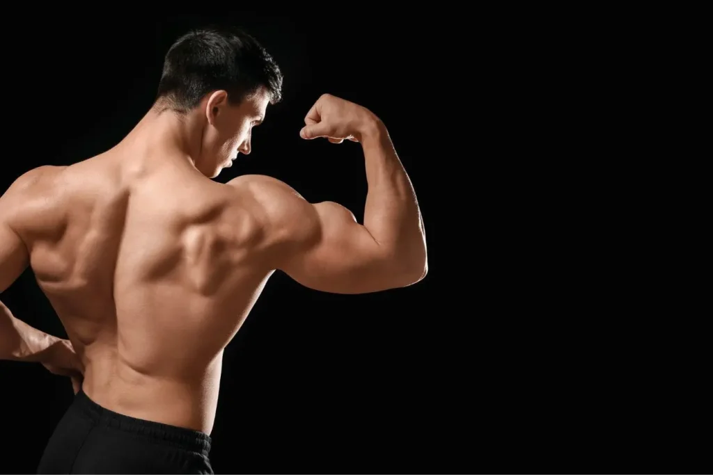 Corps musclé en posture de force sur fond noir, reflet d’un rebond glucidique essentiel pour performance et récupération en musculation