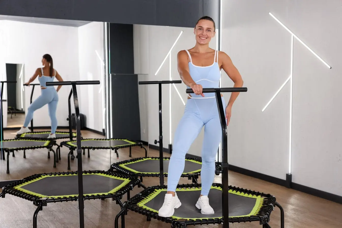 trampoline et fitness Personne en tenue sportive bleue sourit sur trampoline avec guidon, image illustrant le fitness dynamique et ludique par trampoline