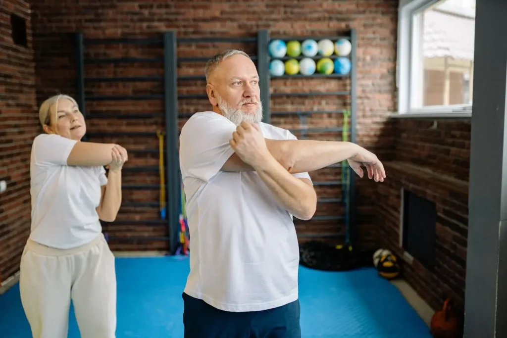 Étirement guidé des bras dans salle équipée, image illustrant exercices pour lymphœdème.