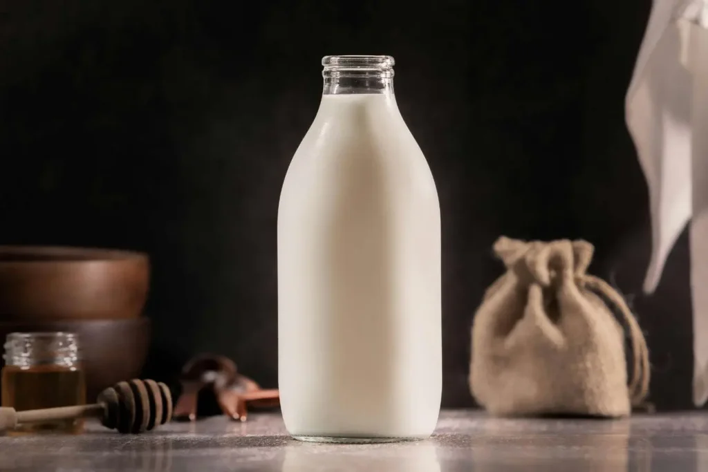 Bouteille de lait posée sur table avec miel et bols, image illustrant des aliments bénéfiques pour accompagner la ménopause et soutenir la santé osseuse.