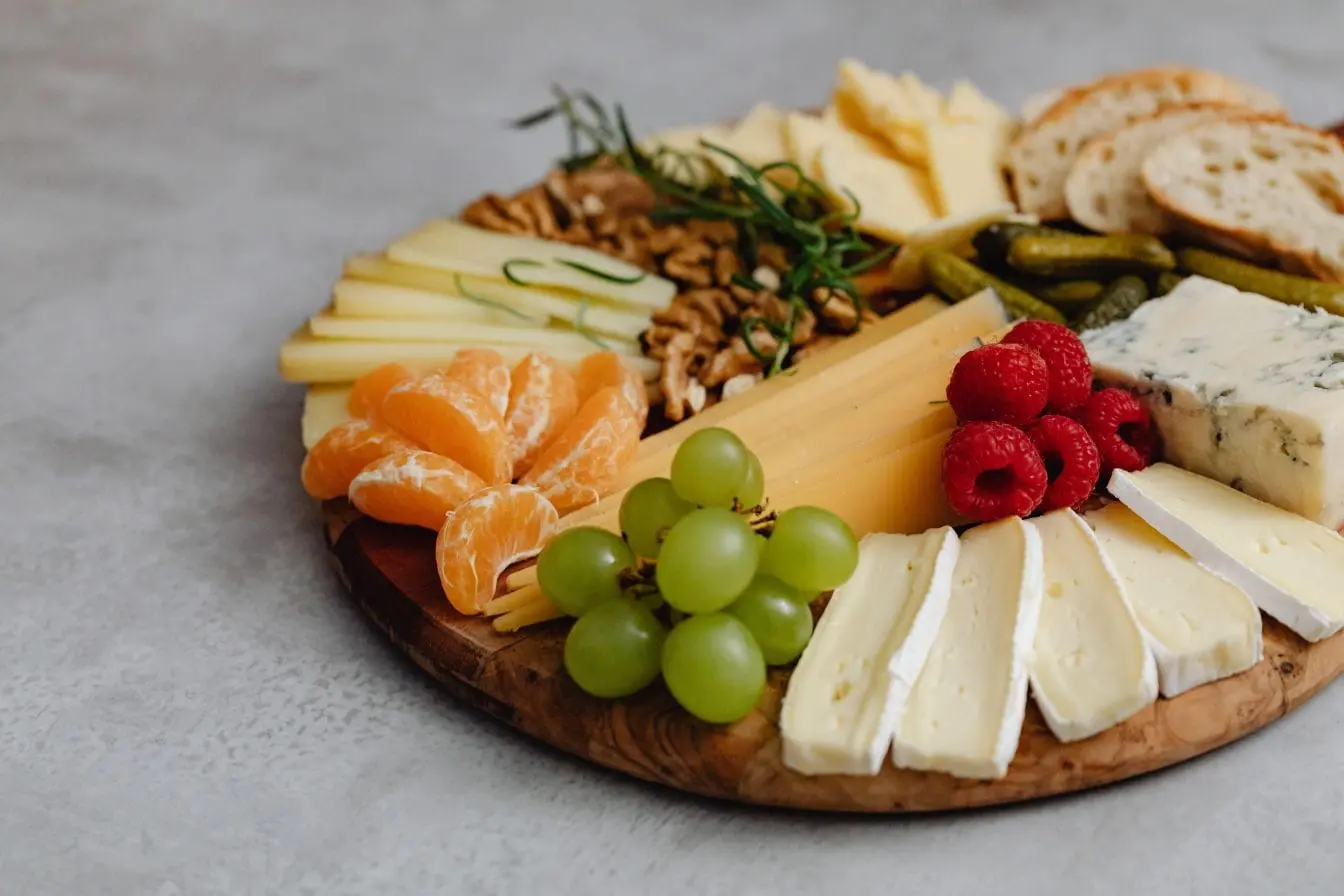 Plateau en bois garni de fromages variés, fruits frais et noix, image illustrant des aliments bénéfiques pour accompagner la ménopause.