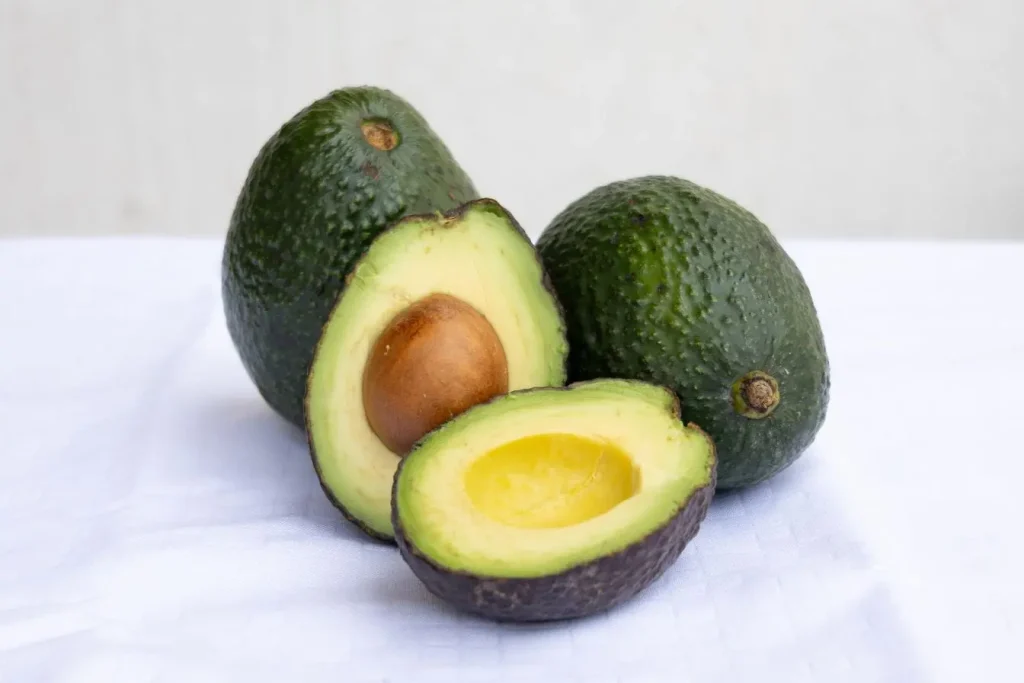 Trois avocats posés sur surface blanche reflétant richesse en bons gras et nutriments essentiels pour soutenir thyroïde par alimentation adaptée contre l’hypothyroïdie.