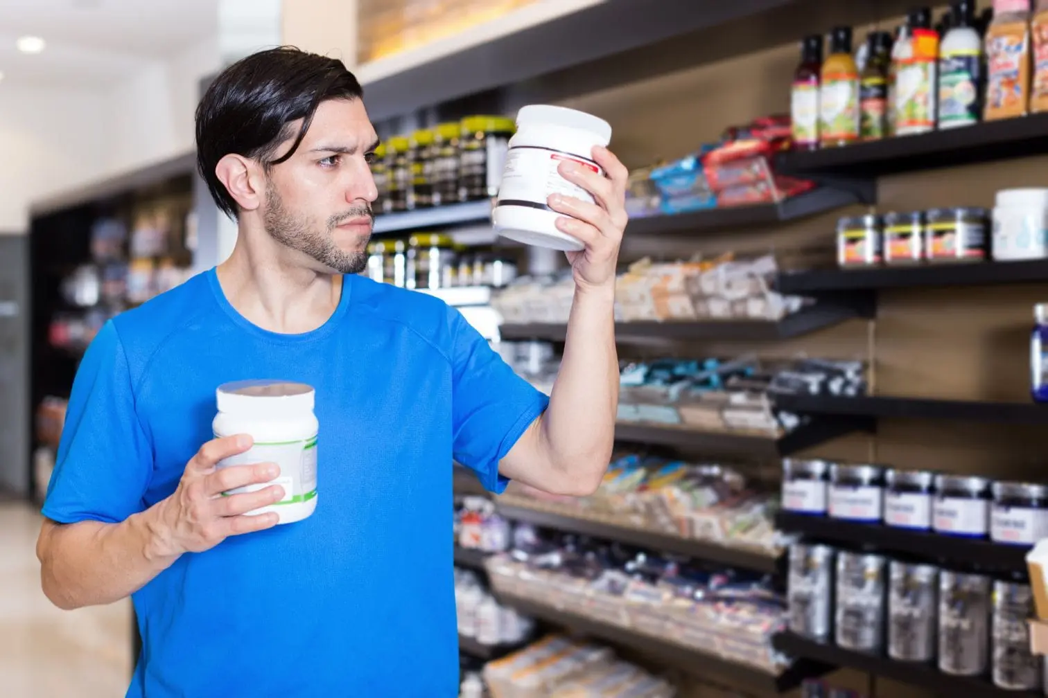Personne en magasin tenant deux contenants évoquant la créatine monohydrate complément alimentaire pour musculation.