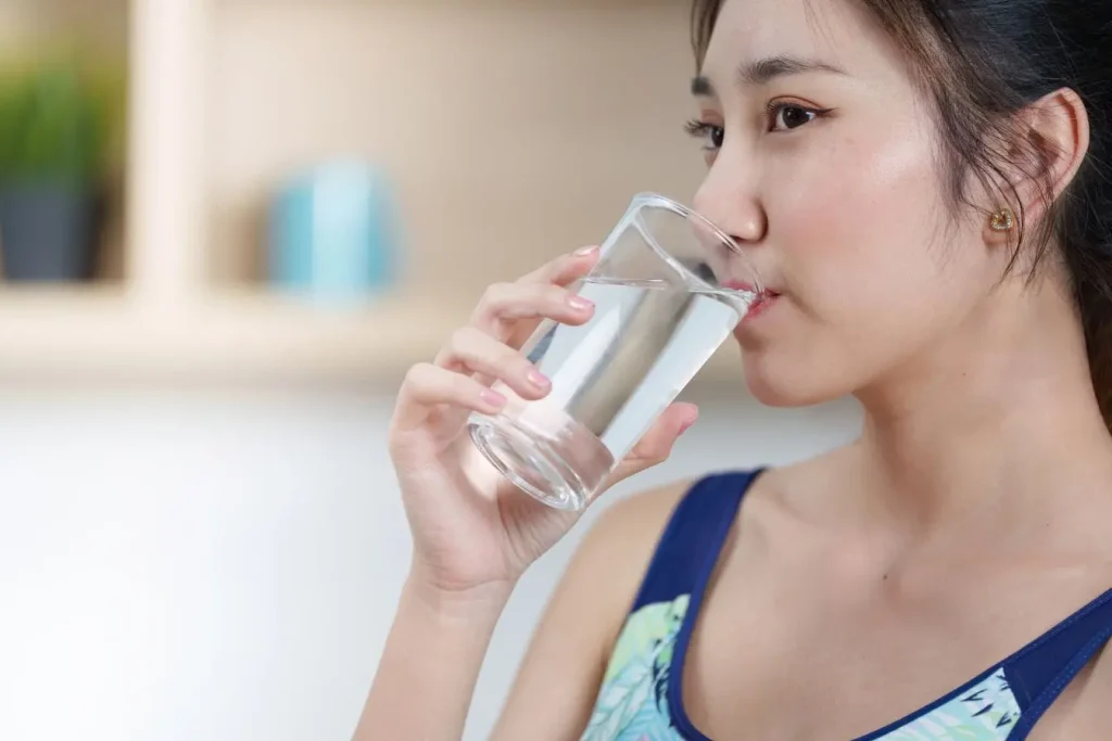 Personne buvant un verre d’eau image représentant l’importance de l’hydratation pour soulager les articulations et favoriser leur confort.