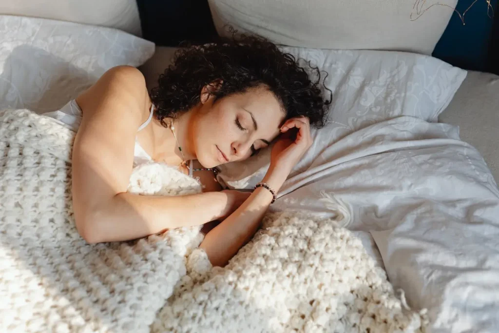 Personne endormie sous couverture douce, image illustrant le lien entre alimentation équilibrée et sommeil réparateur.