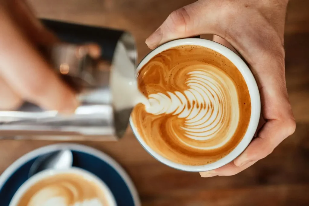 Tasse de café avec lait mousseux, image mettant en avant des aliments inutiles pour la ménopause et la vitalité.