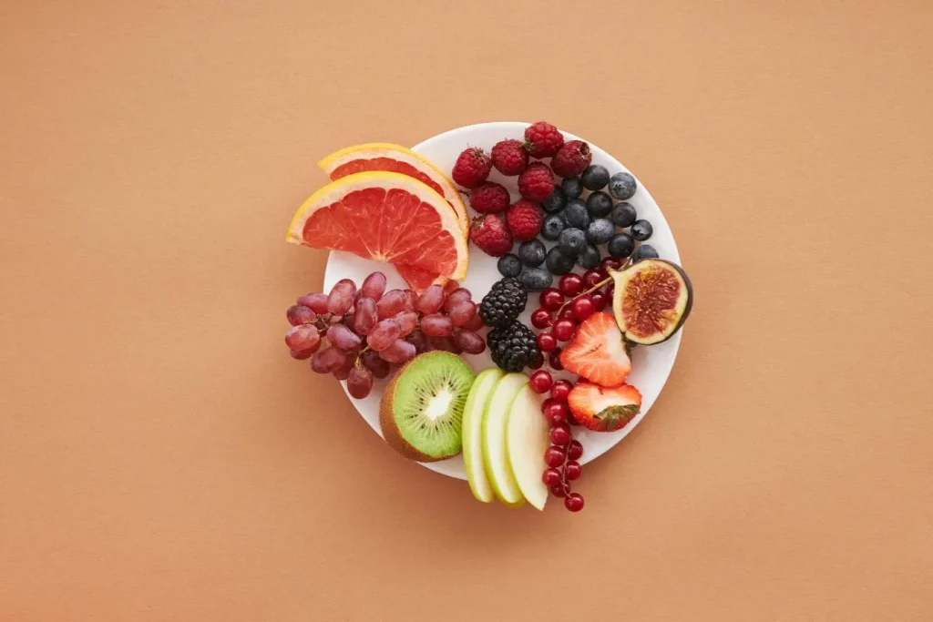 Assiette de fruits colorés avec agrumes, baies et kiwi, image illustrant l’importance d’une alimentation riche en antioxydants pour la santé rénale.