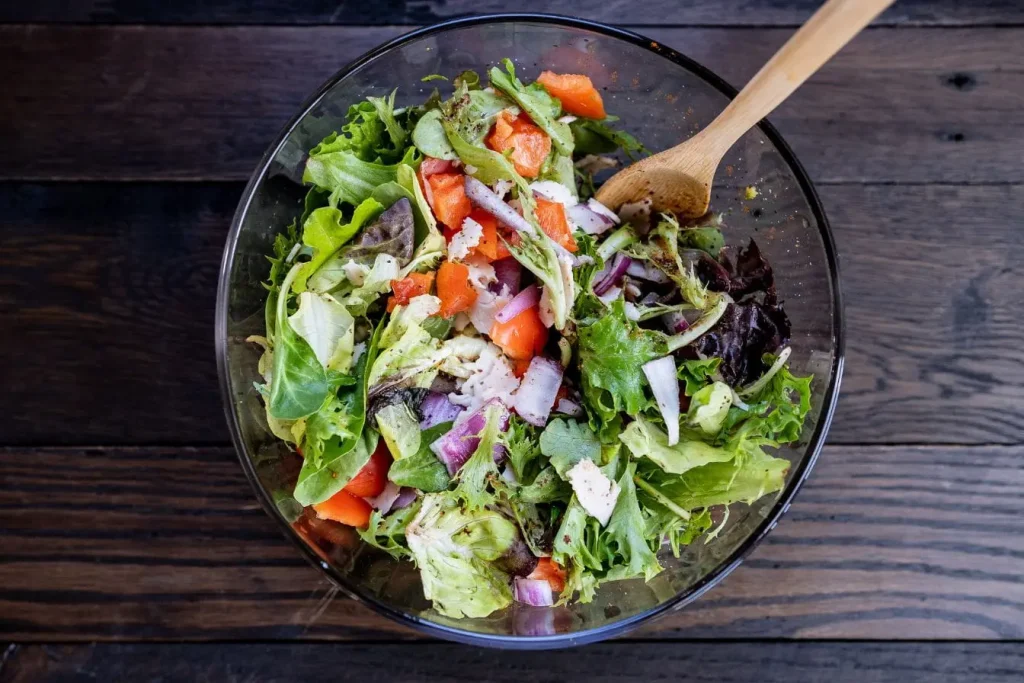 Salade verte garnie de tomates et oignons rouges, reflet d’une nutrition riche en fibres qui contribue à réduire les triglycérides sanguins.