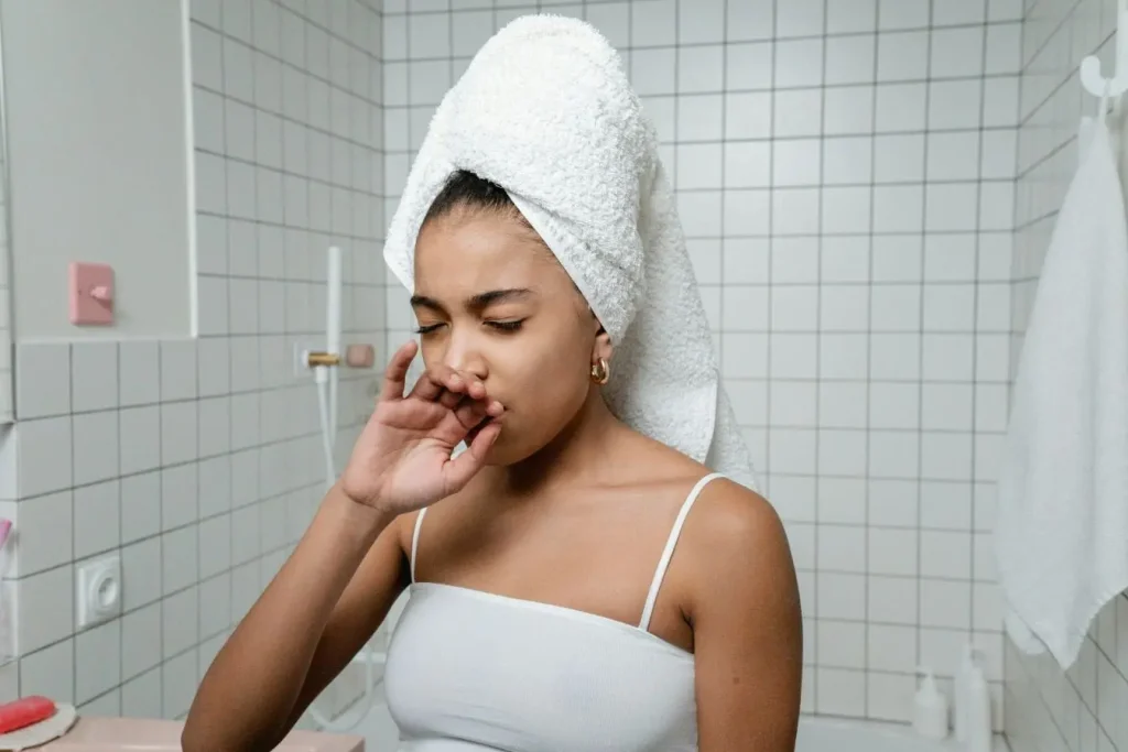 Personne en serviette blanche bâillant dans salle de bain, image illustrant fatigue et troubles digestifs fréquents liés à l’allergie au gluten chez l’adulte.