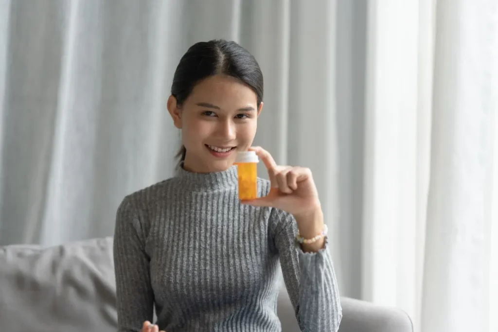 Personne tenant un flacon orange de médicaments, image représentant l’importance de relier SOPK et aliments dans une approche globale de santé.