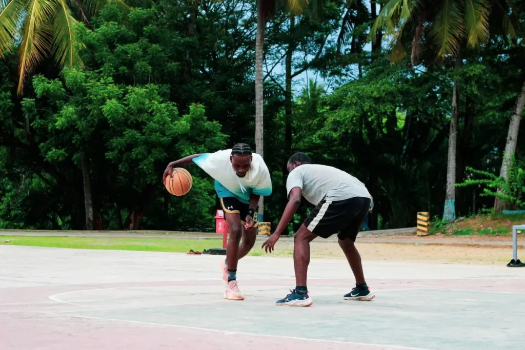 Deux personnes jouent au basketball sur terrain extérieur, image évoquant l’impact de l’activité physique sur la régulation de la tension artérielle.
