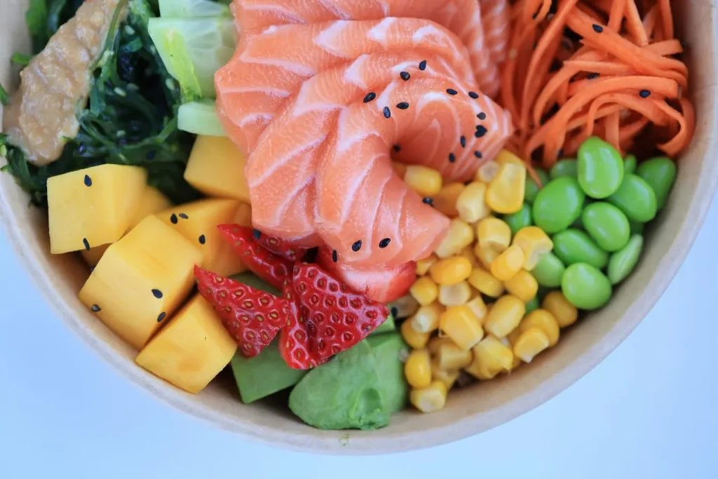 Bol coloré rempli de saumon cru, légumes et fruits, image évoquant une alimentation équilibrée essentielle pour prévenir chute de cheveux liée à carence nutritionnelle.