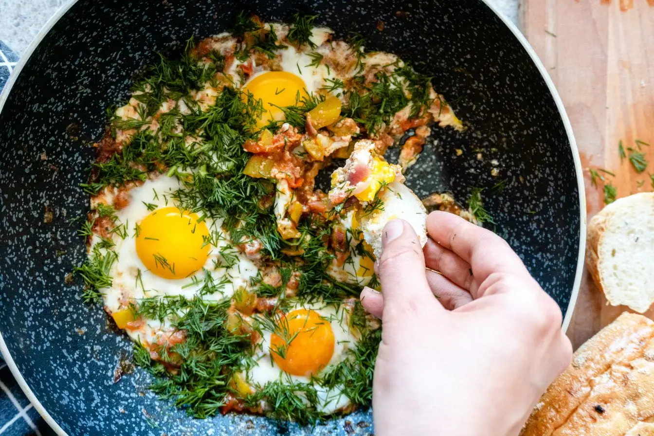 Œufs au plat avec légumes et herbes, image illustrant une recette maison cuisinée sans huile pour un repas plus léger et sain.