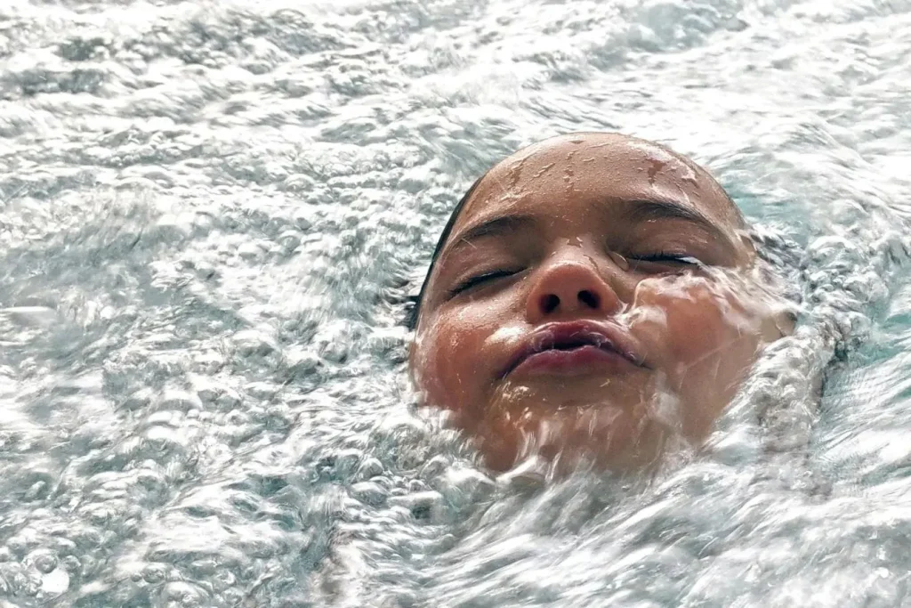 Visage immergé dans eau froide avec bulles et yeux fermés, image illustrant la pratique du bain froid pour favoriser la récupération musculaire.