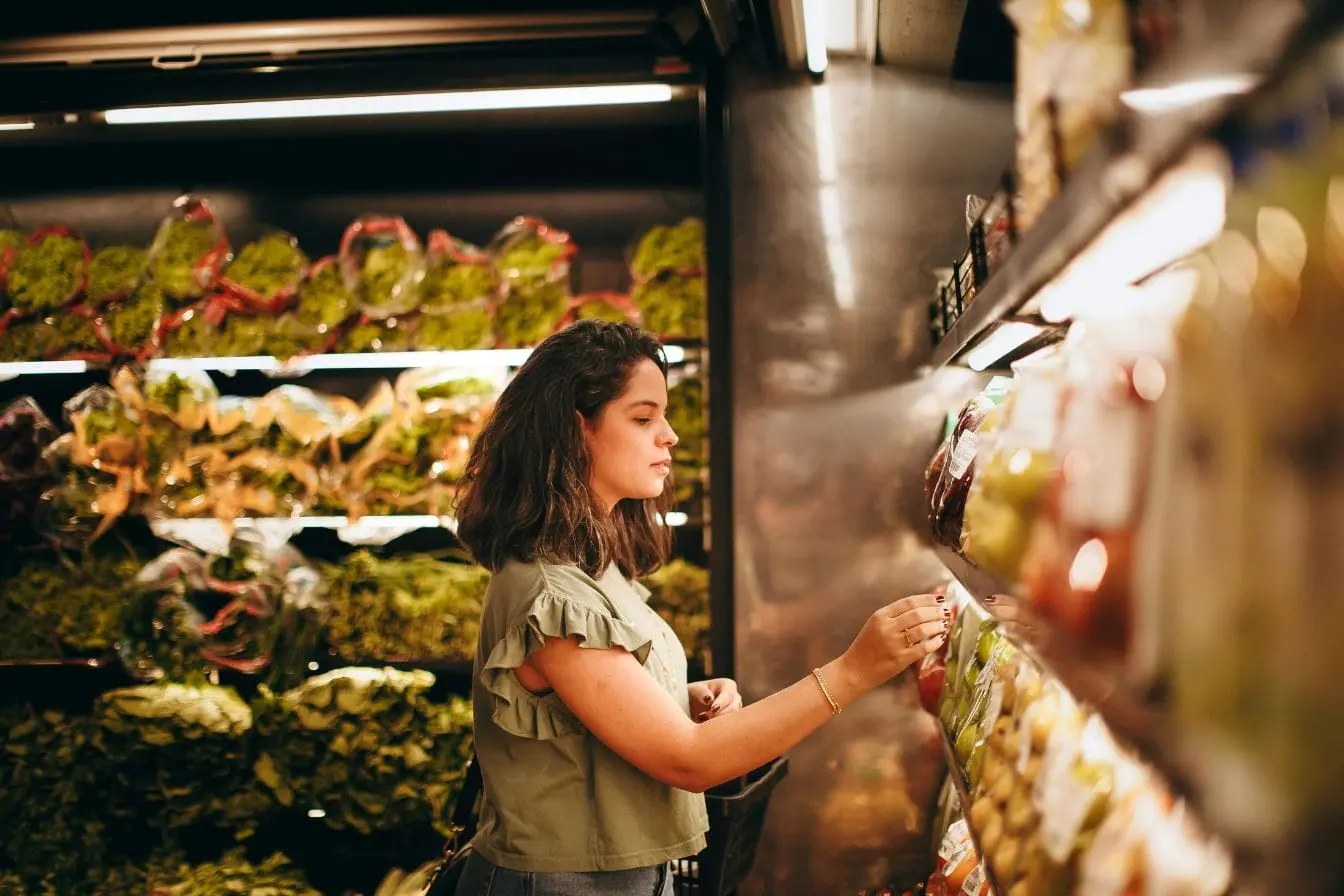 lire une étiquette nutritionnelle Jeune femme examinant attentivement un emballage au rayon frais pour lire une étiquette nutritionnelle et vérifier les ingrédients avant d'acheter son produit.