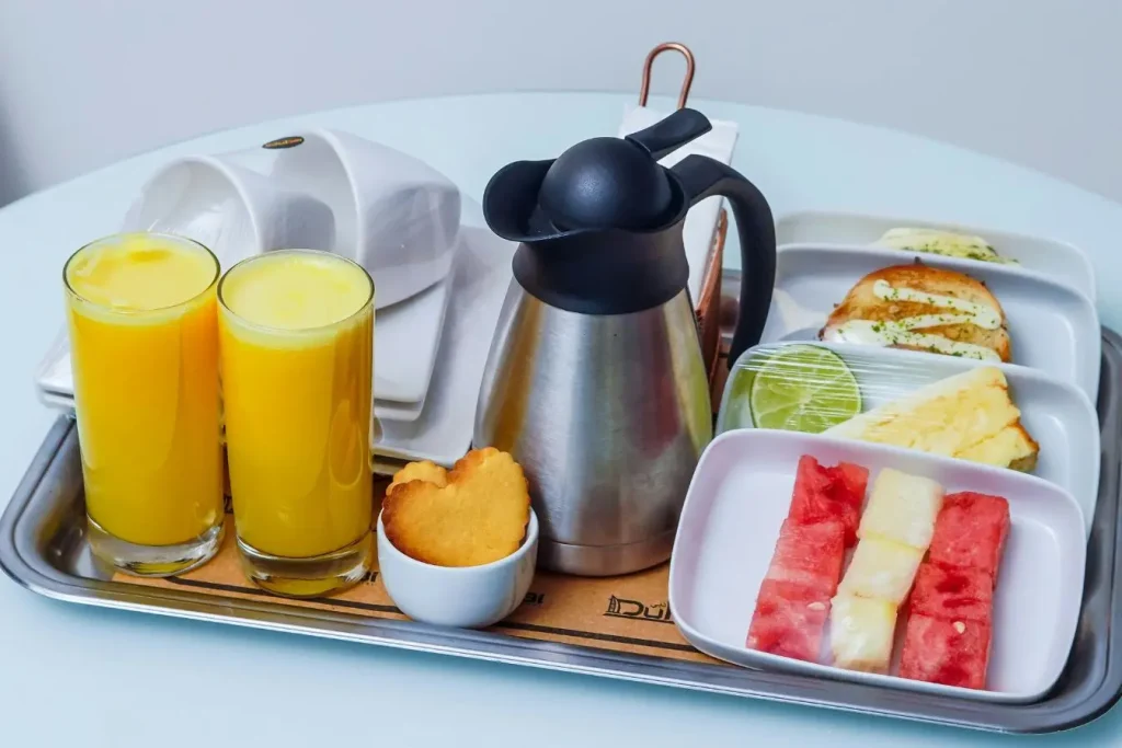 Plateau de petit-déjeuner avec jus, fruits et pain, image illustrant l’importance d’une alimentation équilibrée au premier trimestre de grossesse.