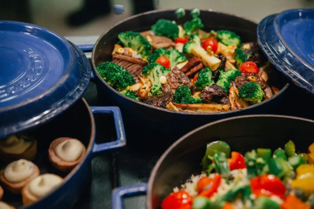 Trois cocottes bleues remplies de plats colorés, image illustrant la préparation maison de recettes variées cuisinées sans huile pour un repas plus sain.
