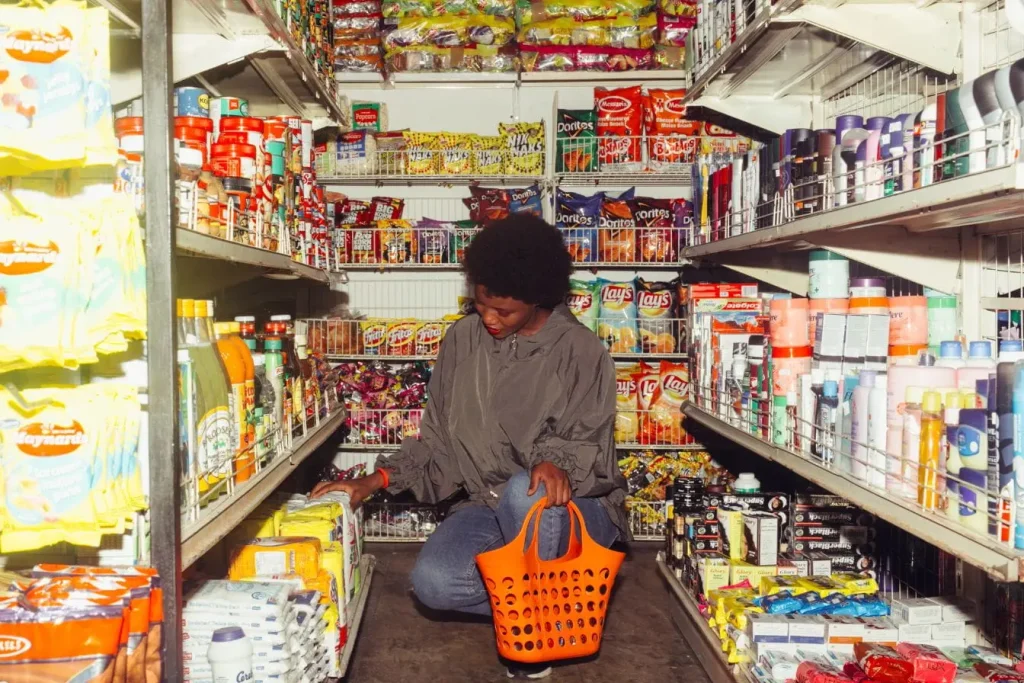 Une cliente avec un panier orange regarde un emballage au bas d'un rayon pour lire une étiquette nutritionnelle