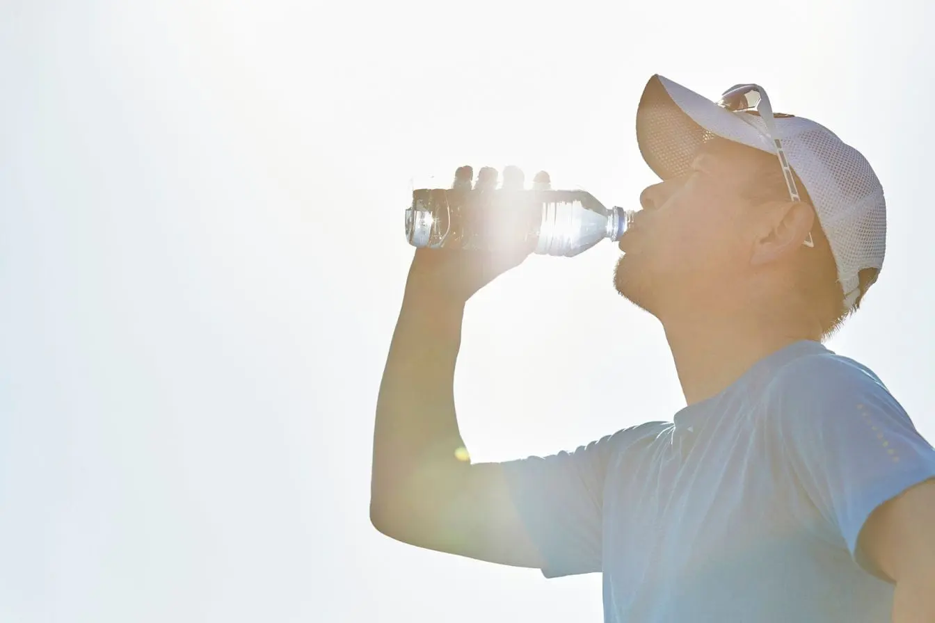 Personne en tenue bleue s’hydratant avec bouteille transparente