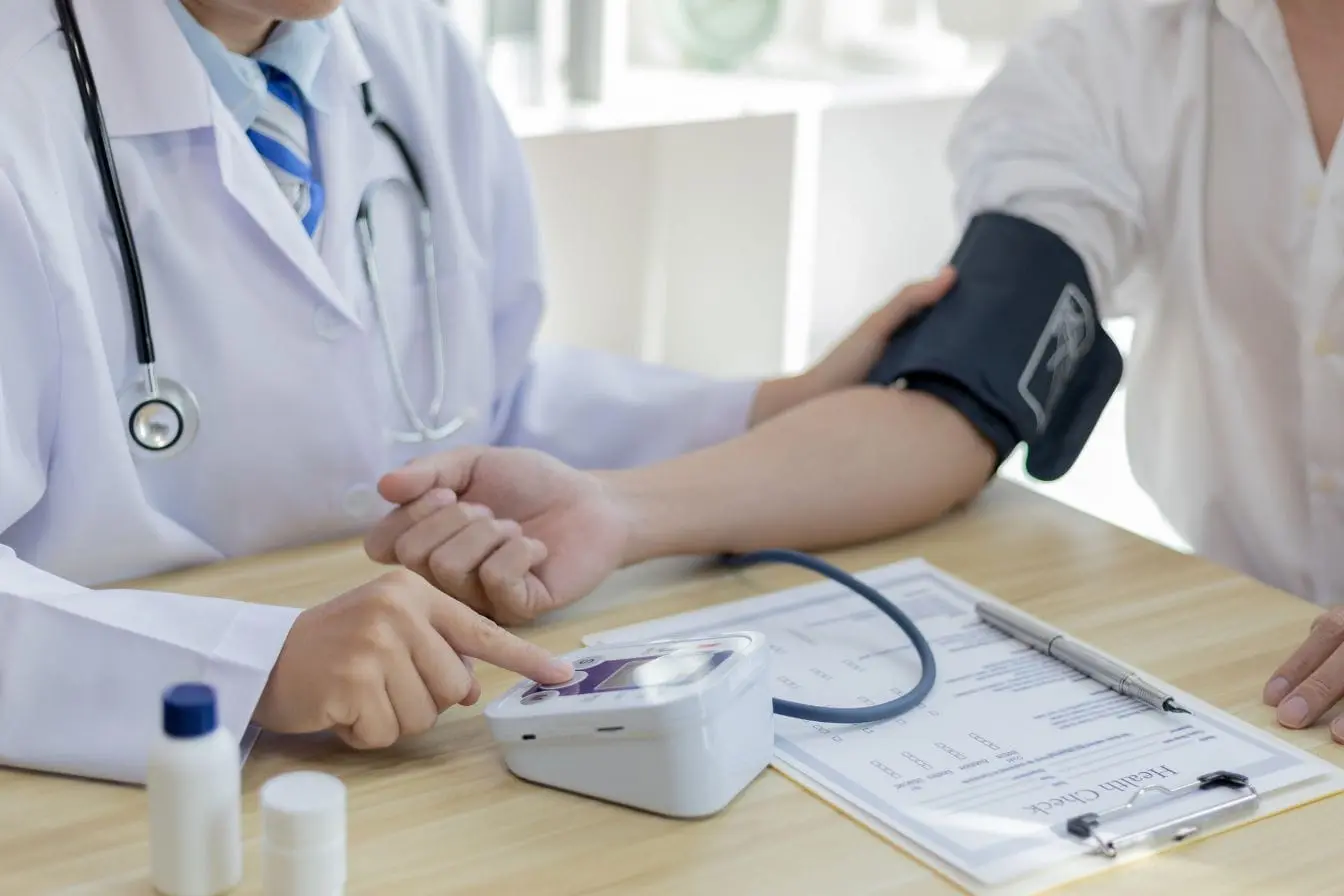 Médecin mesurant la tension d’un patient avec appareil électronique, image évoquant le lien entre alimentation équilibrée et santé cardiovasculaire.
