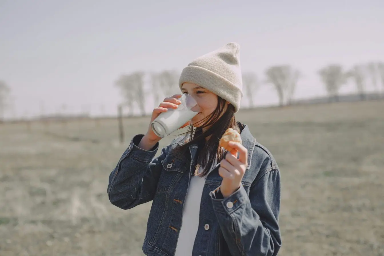Fille au bonnet beige buvant du lait
