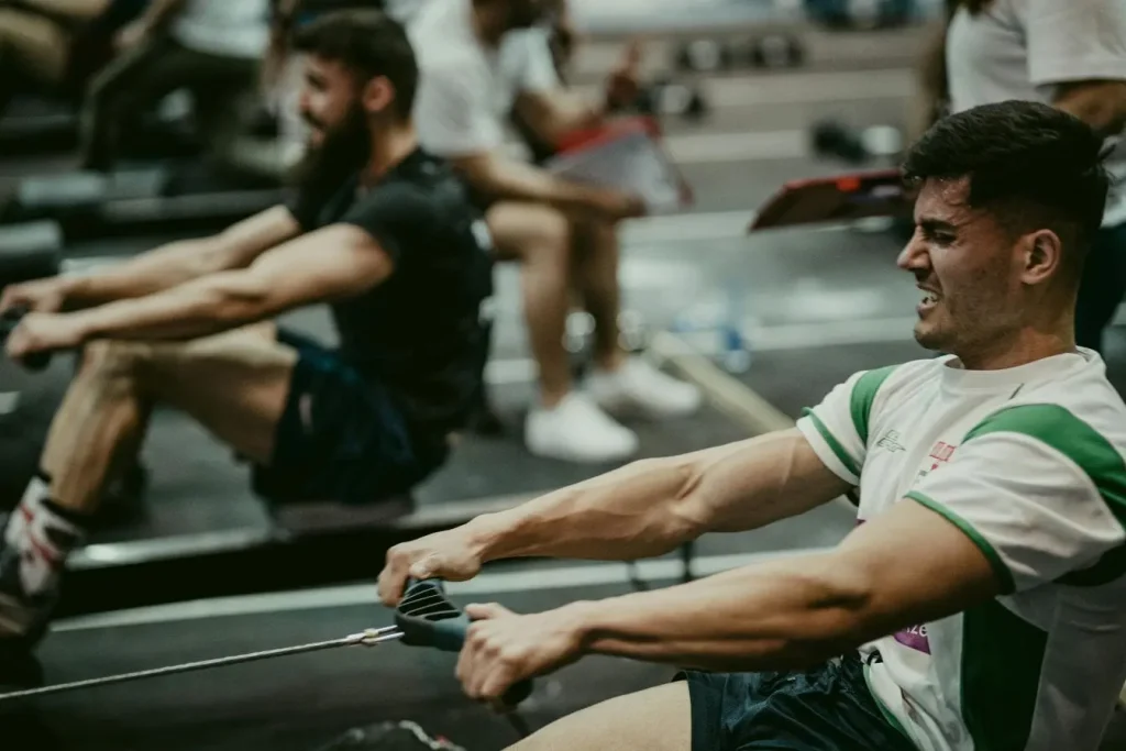 Sportif concentré sur rameur en salle, scène évoquant l’efficacité de l’aviron ergomètre pour renforcer les muscles.