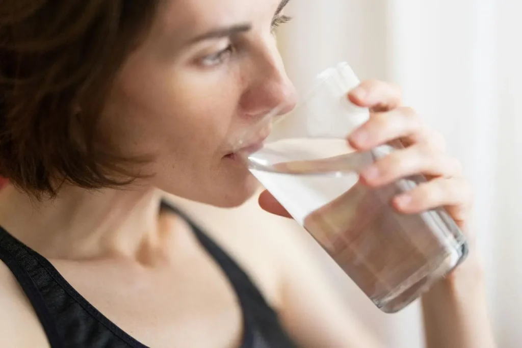 Personne boit un verre d’eau, image illustrant les bienfaits de manger lentement pour mieux ressentir satiété et favoriser digestion.
