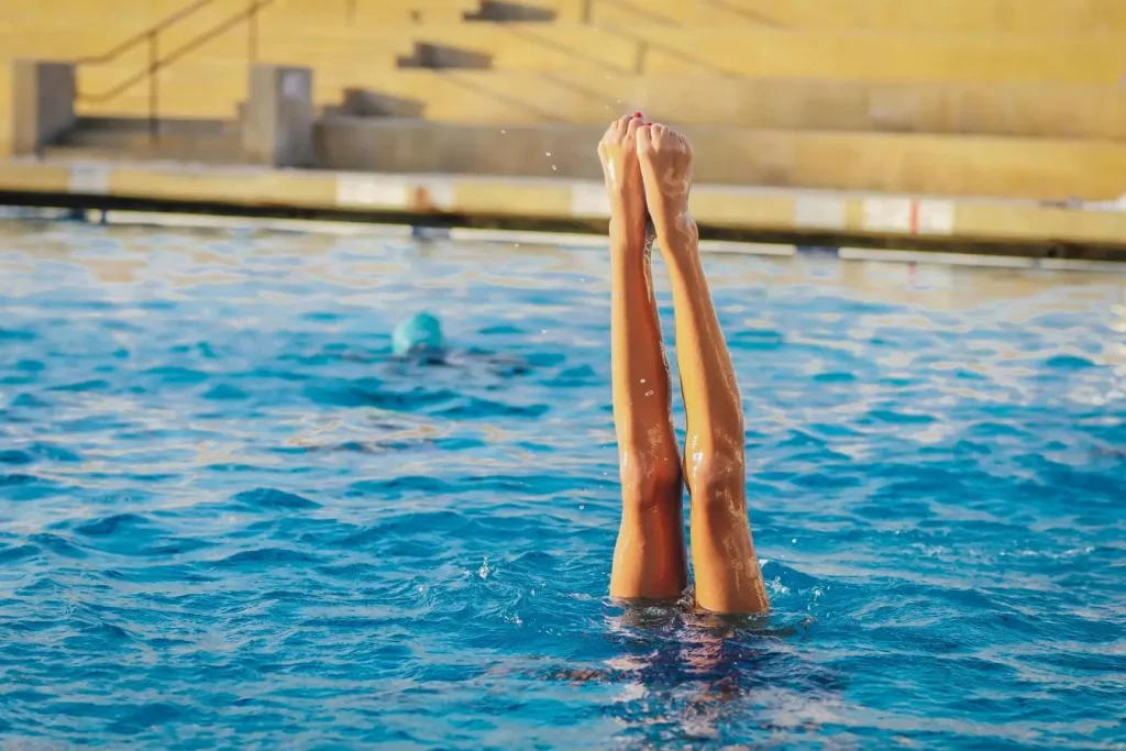 Personne en piscine avec jambes verticales, image représentant aquagym et calories brûlées dans séance sportive.