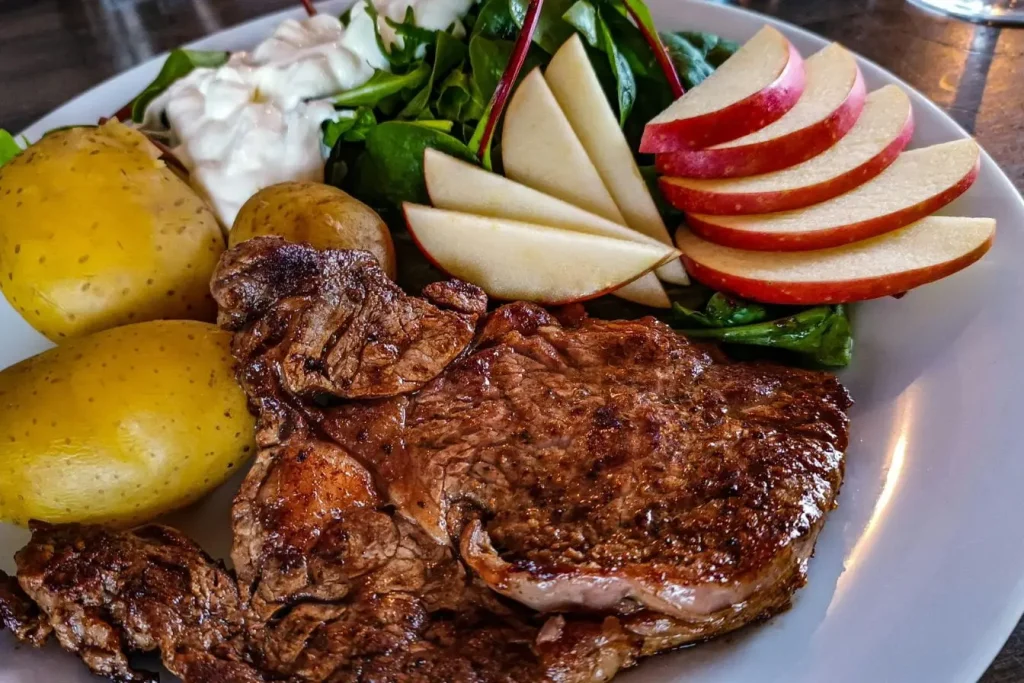 Assiette avec steak grillé, pommes de terre et salade, image illustrant l’index de satiété des aliments et leur effet sur la faim.