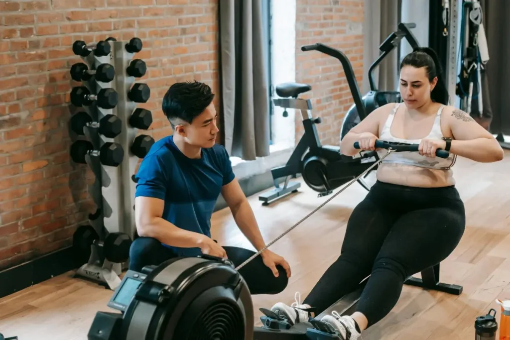 Sportif assis sur rameur indoor tirant la poignée, image illustrant l’efficacité de l’aviron ergomètre pour renforcer les muscles.