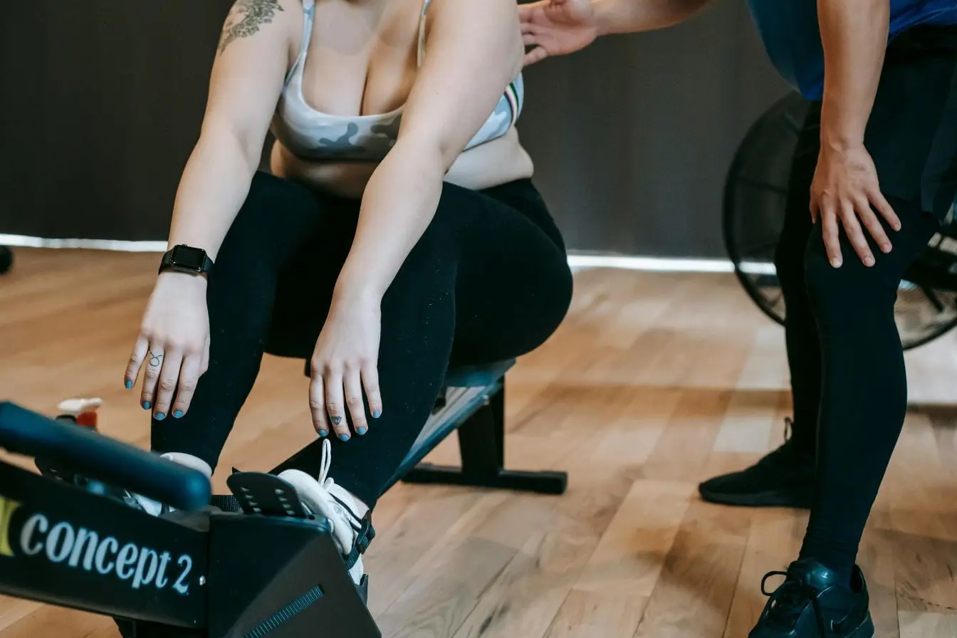 Personne assise sur ergomètre Concept2 en plein effort, image illustrant l’entraînement d’aviron et son rôle dans la musculation.
