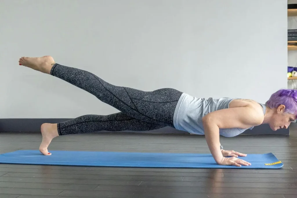 Personne en posture de yoga sur tapis bleu, bras fléchis et jambe tendue, illustrant un exercice de proprioception et d’équilibre.