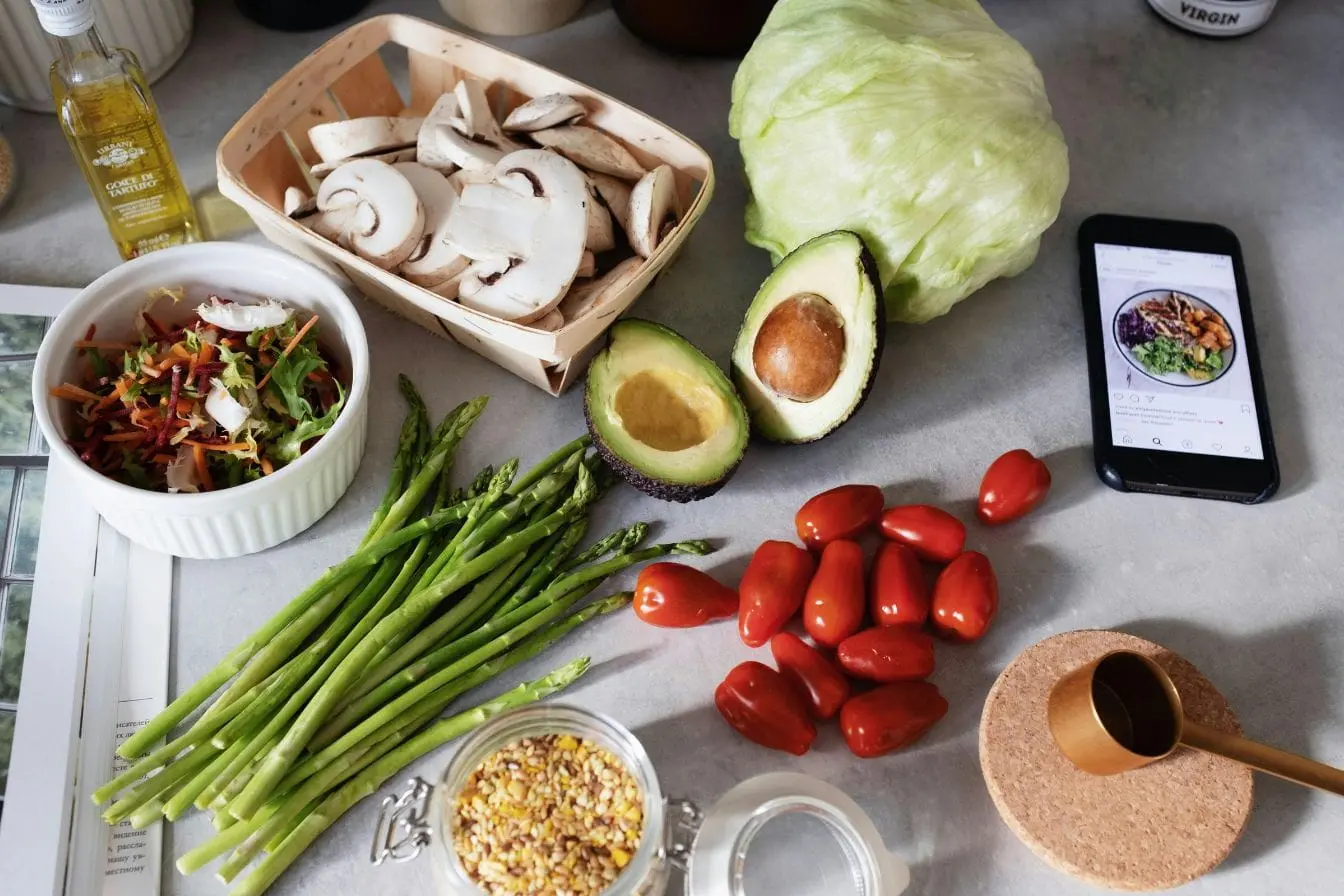 Plan de travail avec légumes frais et smartphone, image illustrant l’alimentation intuitive basée sur écoute du corps et choix naturels.