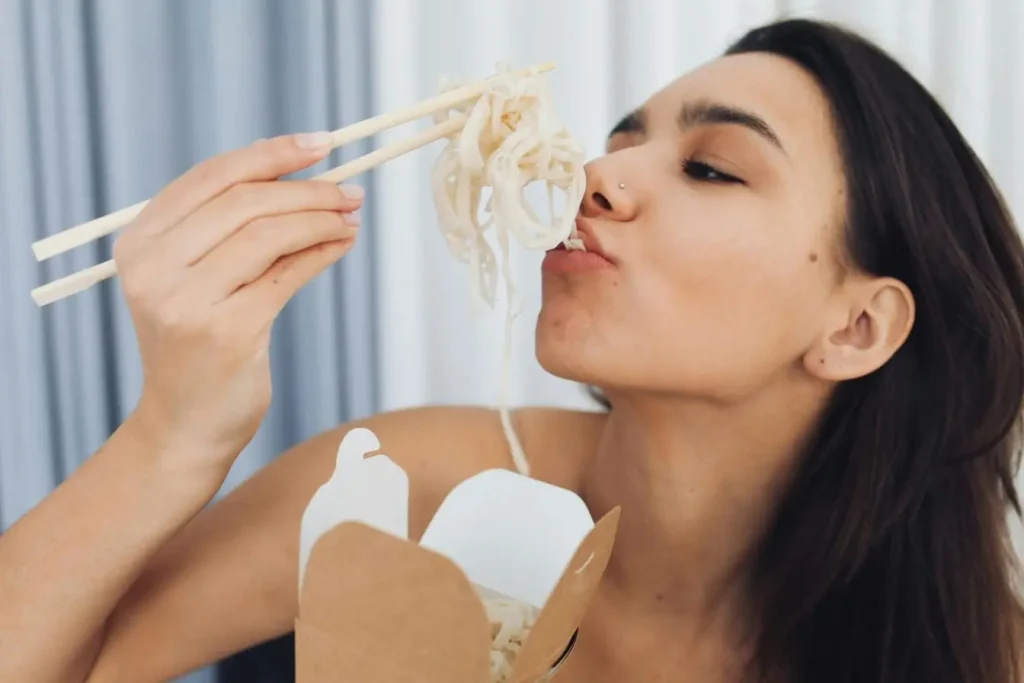 Personne mange des nouilles avec baguettes, image illustrant les bienfaits de manger lentement pour améliorer la digestion
