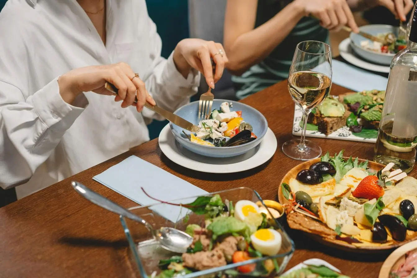Table conviviale avec plats variés et vin, image illustrant les bienfaits de manger lentement pour savourer chaque bouchée et améliorer digestion.