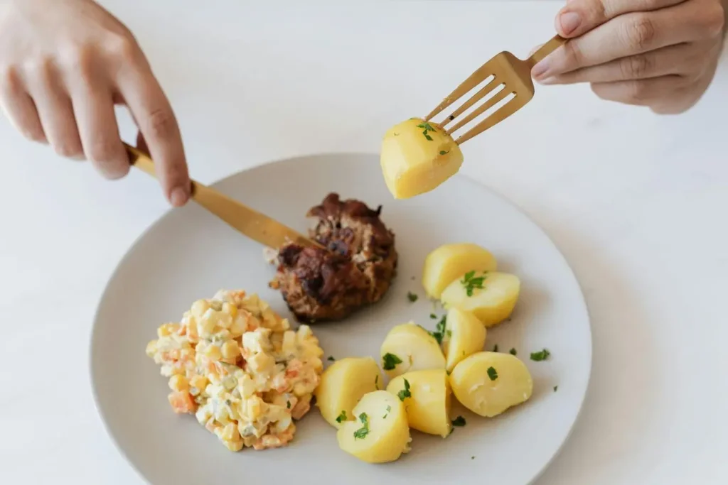 Assiette avec pommes de terre, salade et viande, image illustrant l’index de satiété des aliments et leur impact sur la faim.