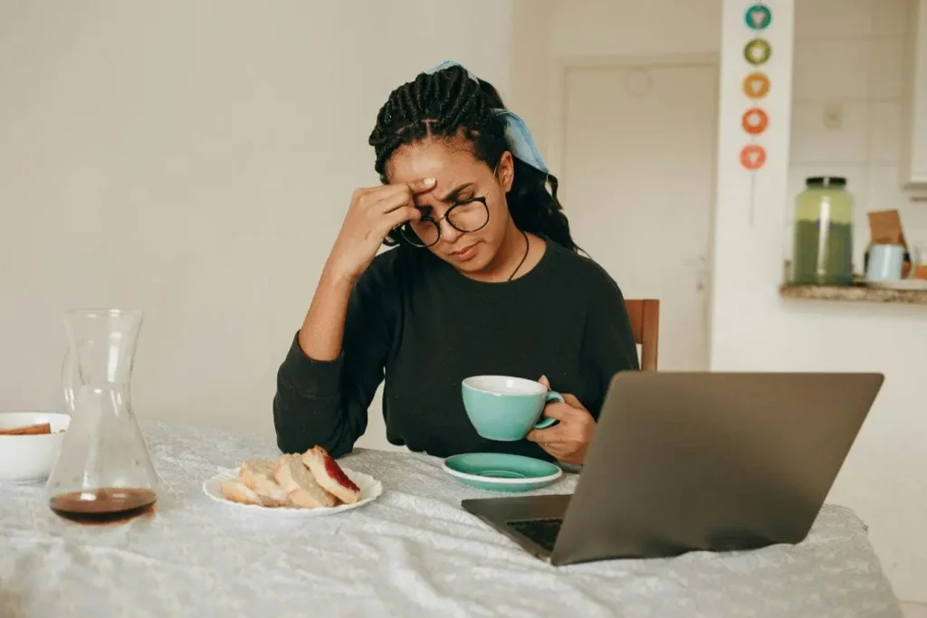 Scène de travail avec ordinateur, tasse et pain représentant la relation entre stress et alimentation excessive.
