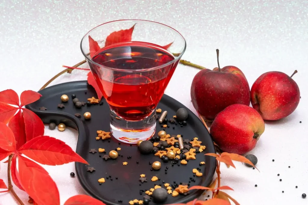 Trois pommes rouges disposées près d’un verre coloré, symbole des bienfaits des enzymes digestives naturelles.