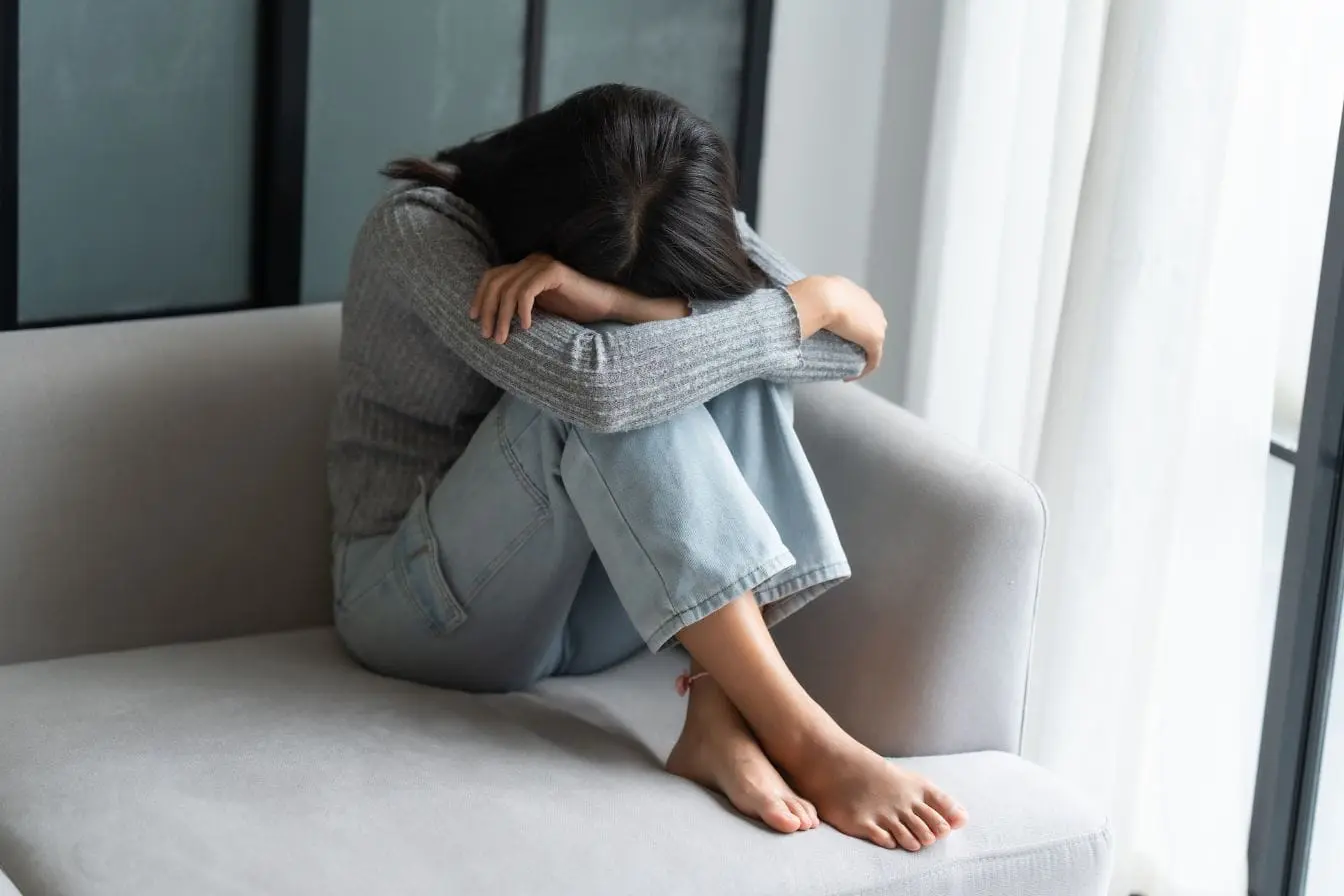 Personne assise recroquevillée sur canapé, image qui illustre la fatigue liée à la dépression saisonnière et l’importance de l’alimentation pour l’énergie.