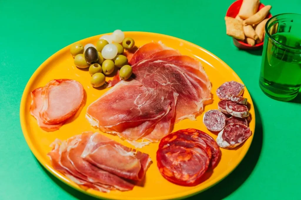Assiette jaune remplie de charcuterie et olives, image qui illustre l’impact d’une alimentation riche en sel et graisses sur la calcification artérielle.