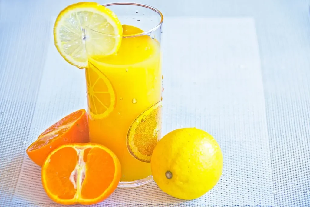 Verre de jus orange garni de citron, image illustrant une boisson maison riche en électrolytes pour hydratation naturelle.