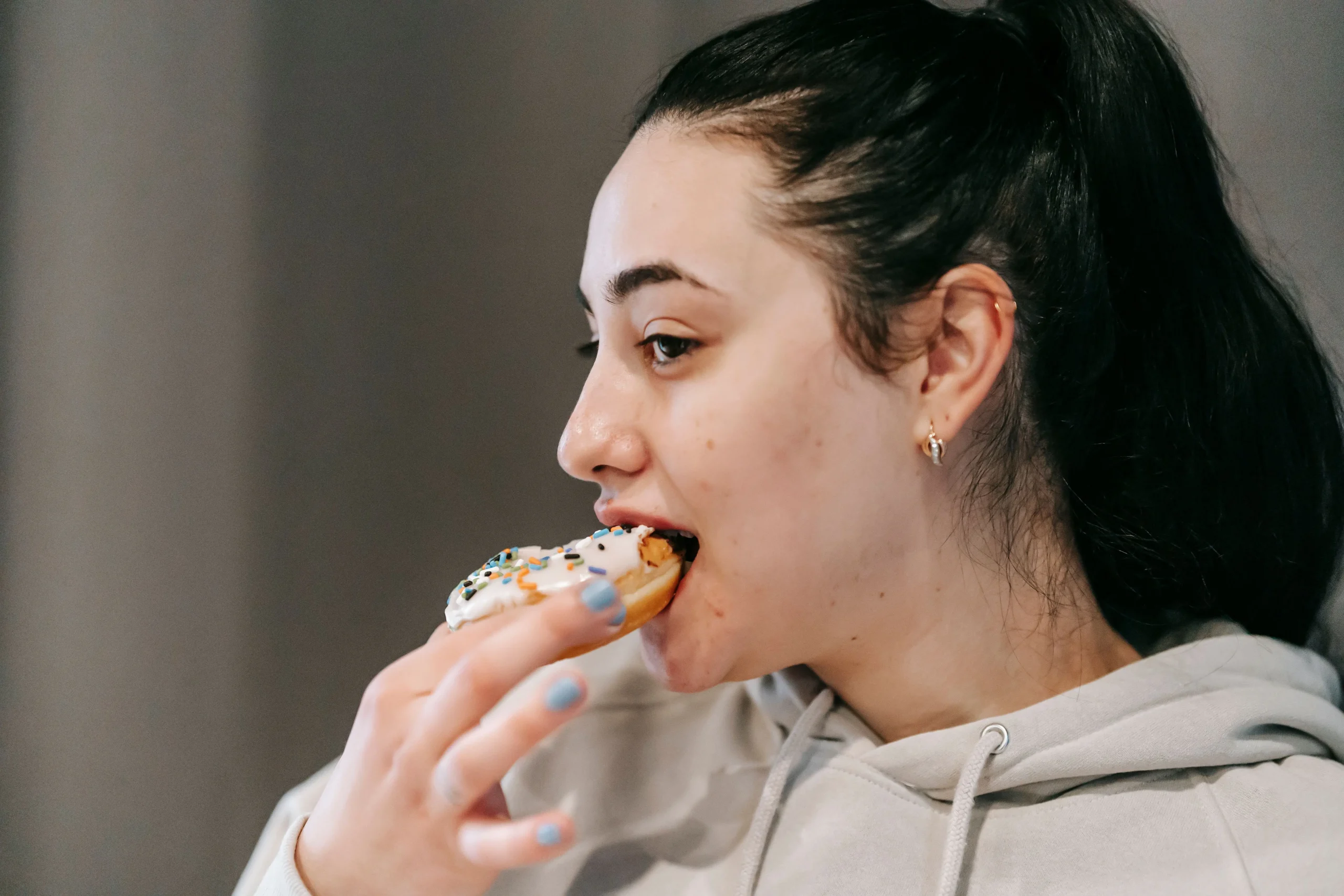 Donut coloré avec glaçage blanc, illustration des aliments sucrés pouvant aggraver l’acné adulte.