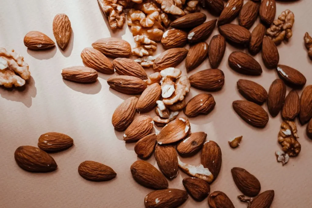 Gros plan sur amandes et noix posées sur surface claire, image qui illustre le rôle protecteur de certains aliments contre la calcification artérielle.